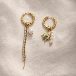 Pair of gold hoop earrings with pearl and starfish charms on a beige fabric background