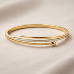 Gold bangle with diamond accents on a beige background