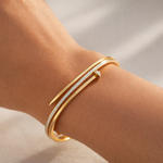 Gold bracelet with diamonds on a wrist against a neutral background