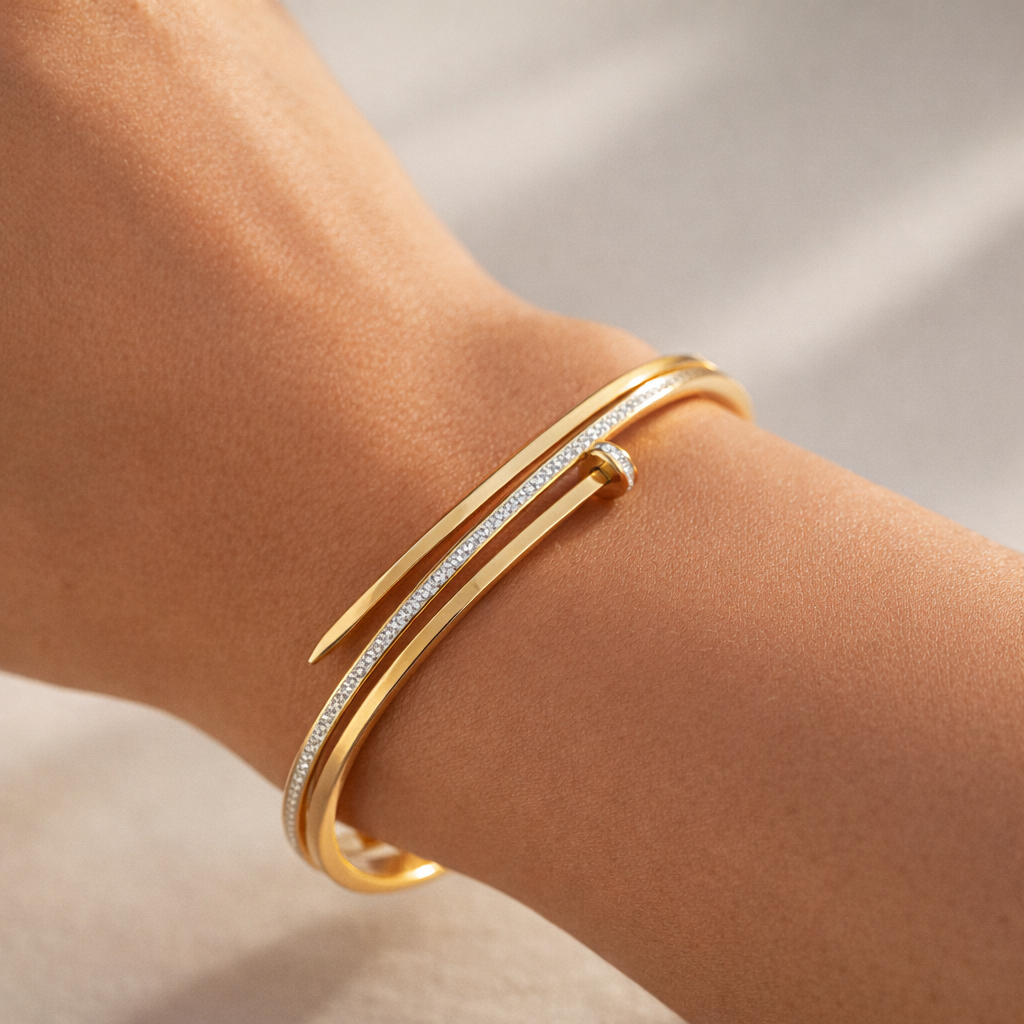 Gold bracelet with diamonds on a wrist against a neutral background