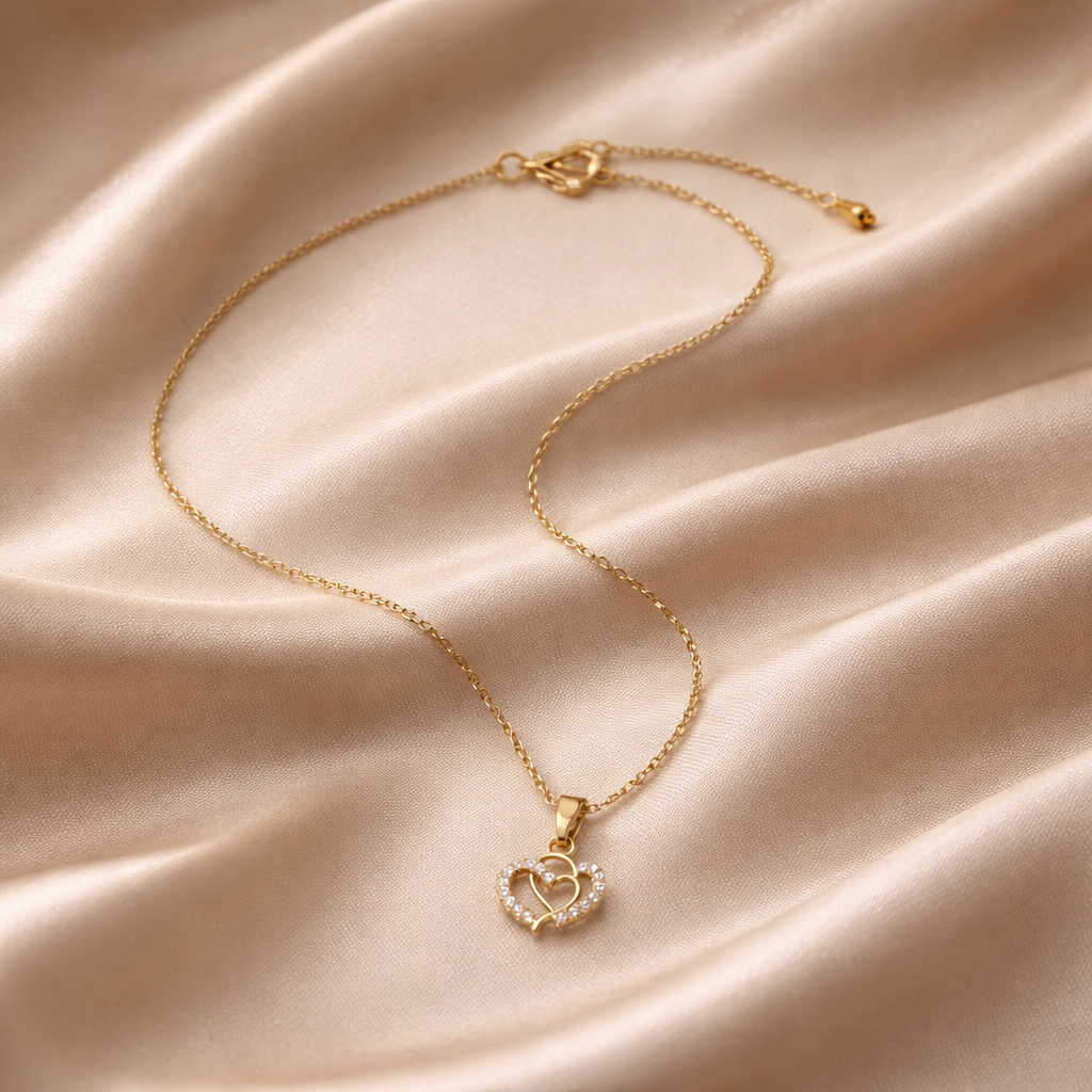 Gold necklace with a heart-shaped pendant on a satin surface
