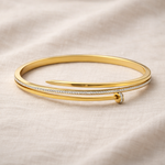 Gold bangle with diamond accents on a beige fabric background