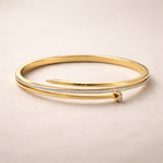 Gold bangle with diamond accents on a beige background