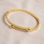 Gold bracelet with diamond accents on a beige background
