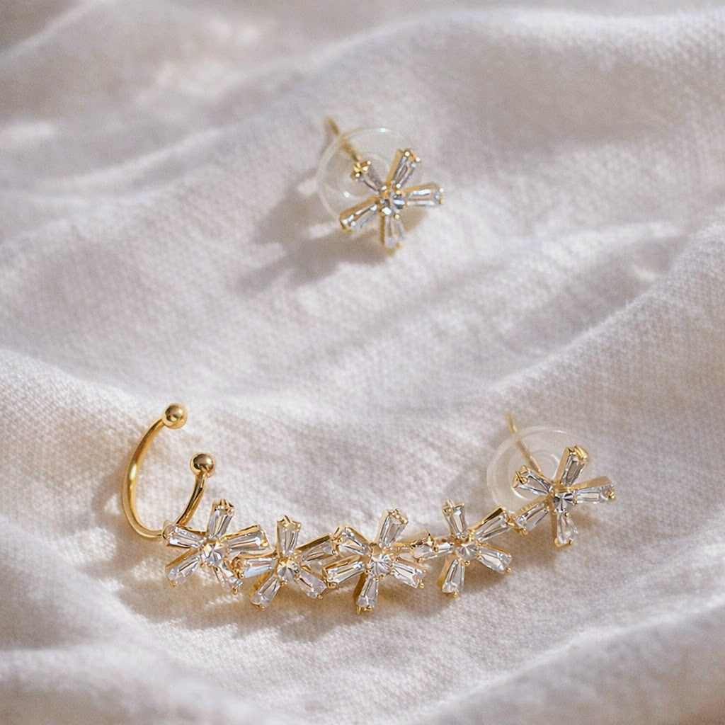 Gold and crystal earring set on a soft beige fabric background