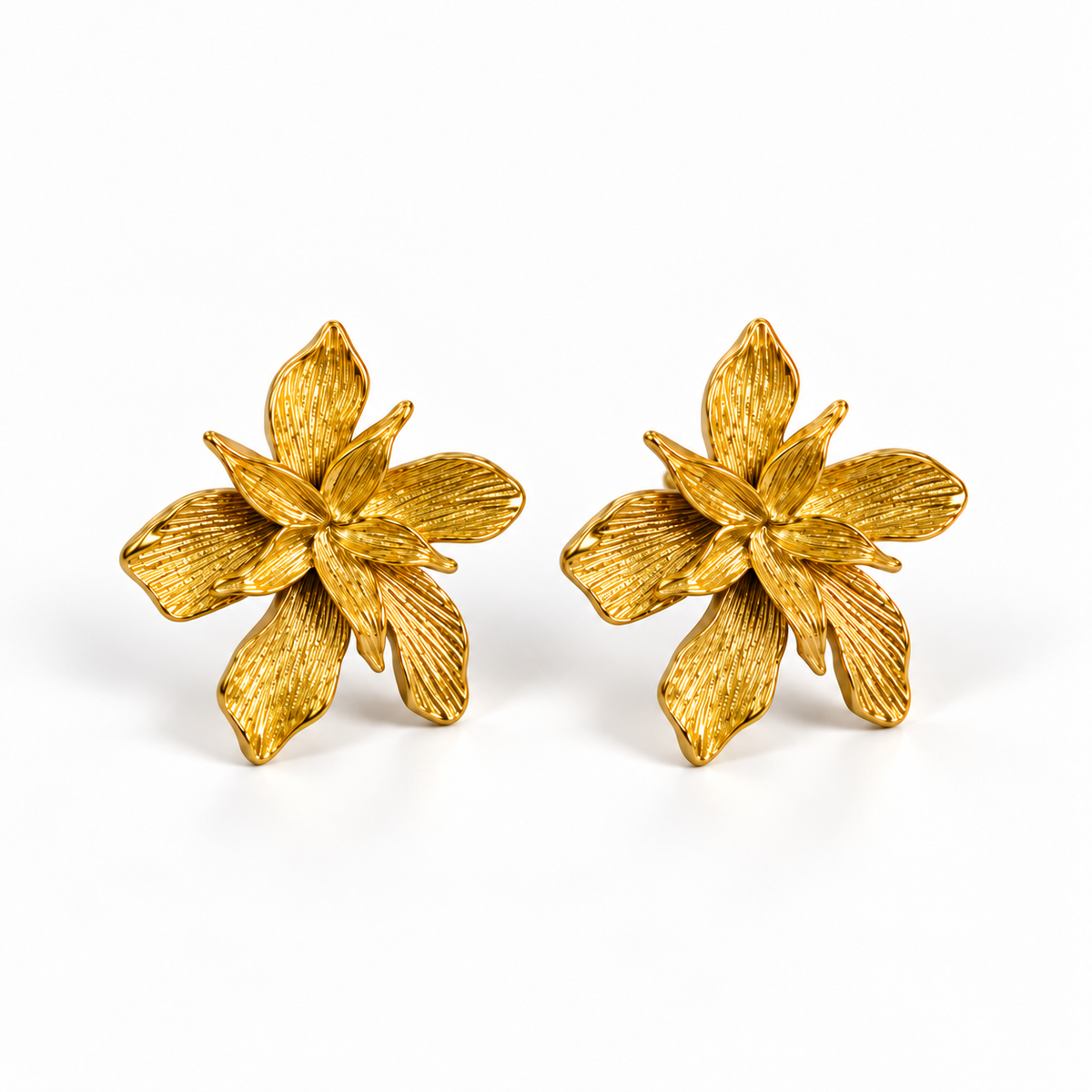 A pair of textured gold flower-shaped earrings on a clean white background.