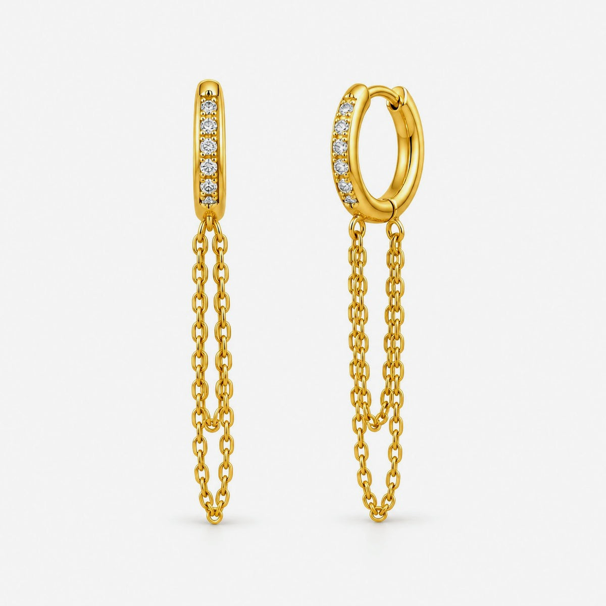 A pair of gold huggie hoop earrings with a vertical bar of small clear stones on one side and a dangling double-chain design on the other, shown on a clean white background.