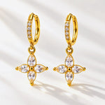 A pair of gold huggie hoop earrings with dangling floral cross charms, set with clear marquise and round-cut stones, displayed on a clean white background with soft shadows.