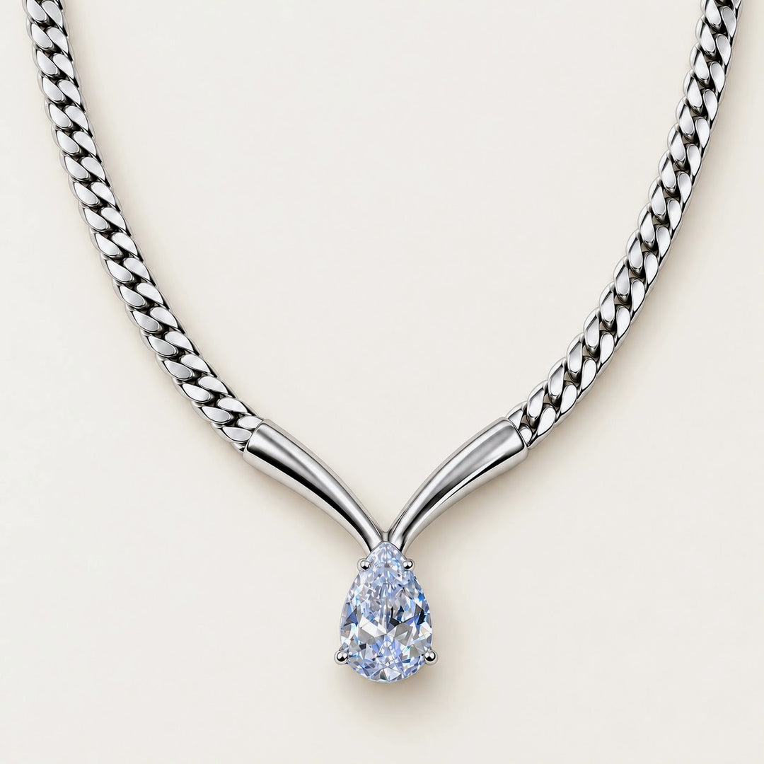 A silver-toned Y-shaped chain necklace with a pear-cut light blue gemstone pendant, shown on a clean off-white background.