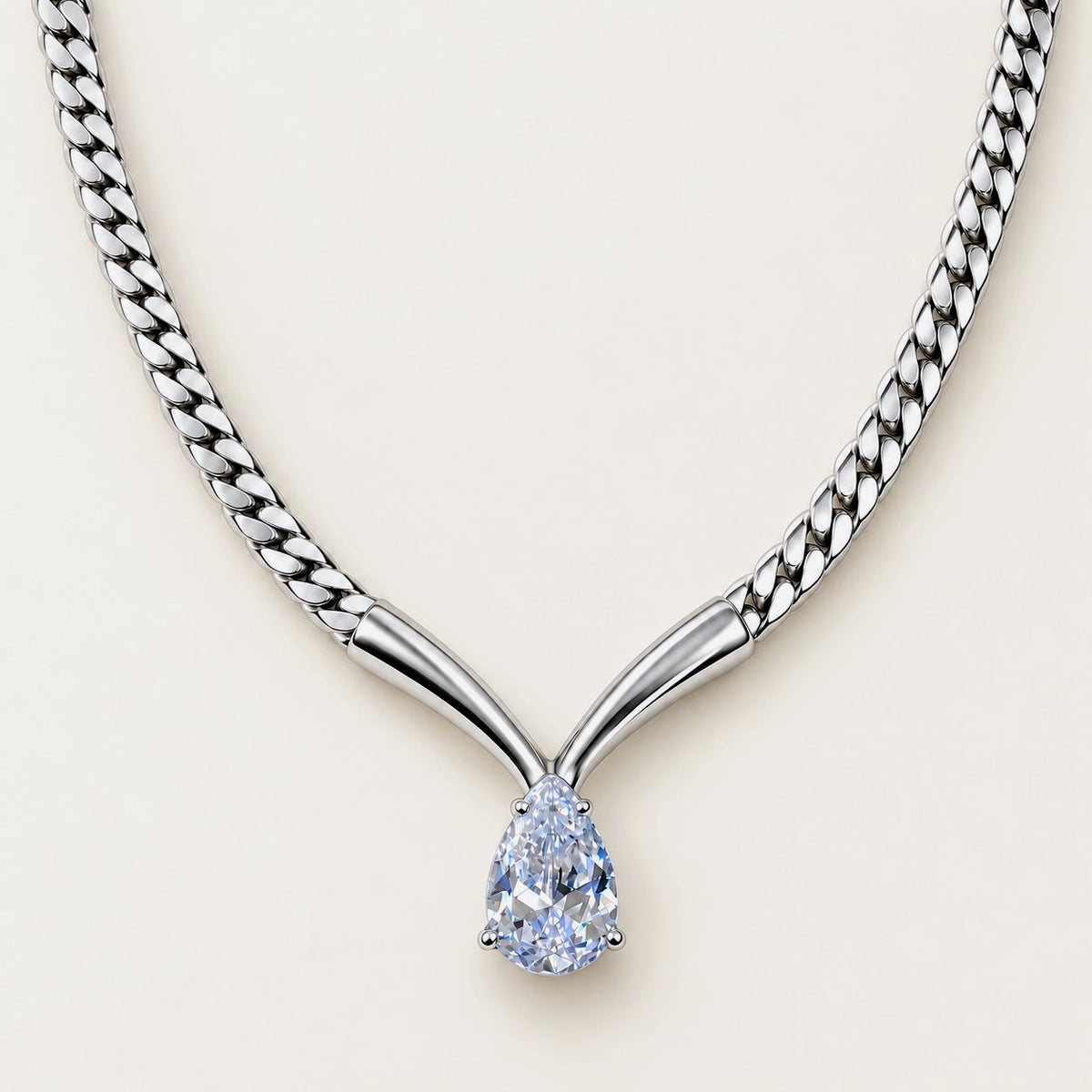 A silver-toned Y-shaped chain necklace with a pear-cut light blue gemstone pendant, shown on a clean off-white background.