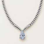 A silver-toned Y-shaped chain necklace with a pear-cut light blue gemstone pendant, shown on a clean off-white background.