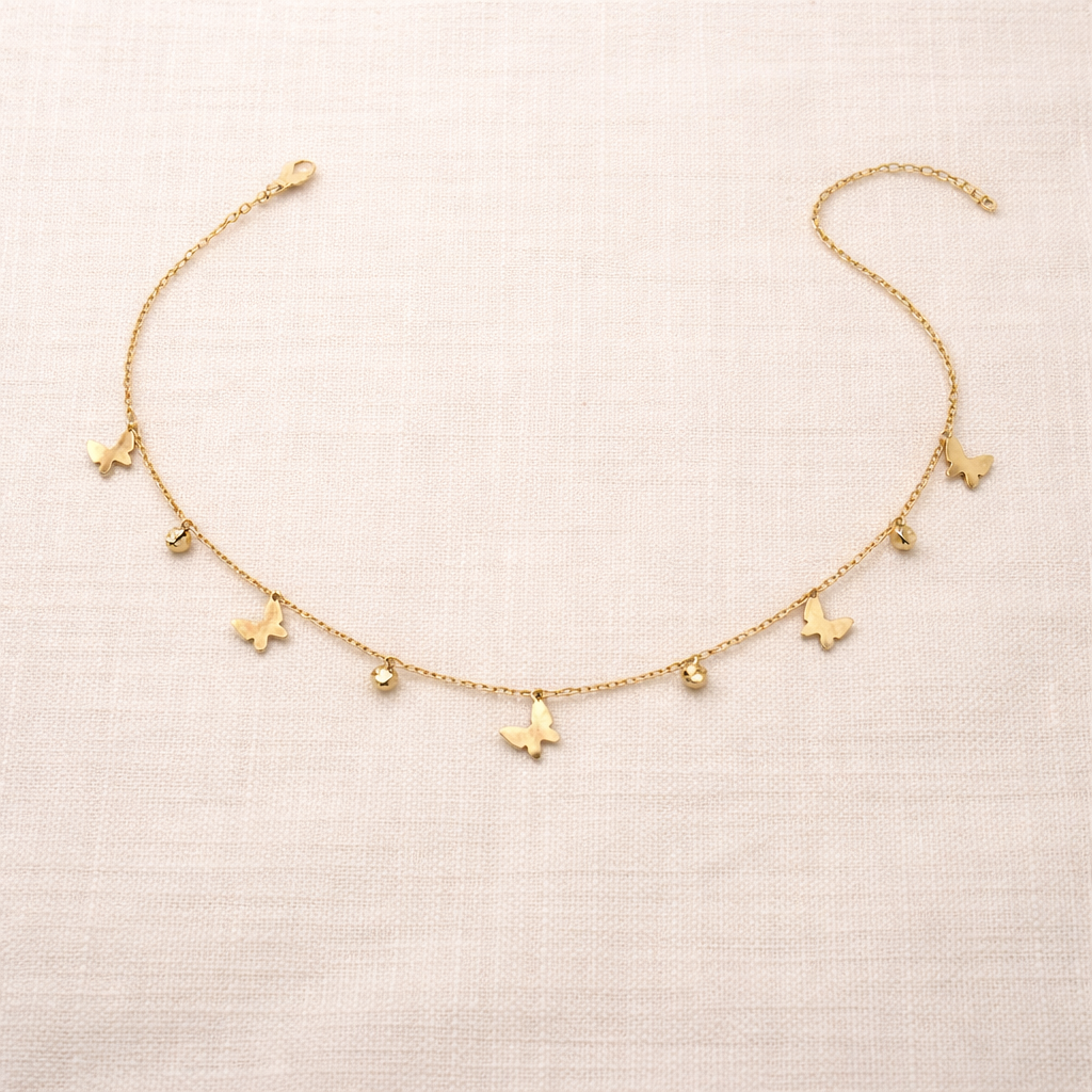 Gold necklace with butterfly charms on a beige fabric background